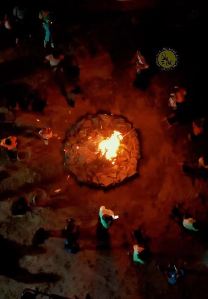 A bonfire at night seen from above, people gathered around it