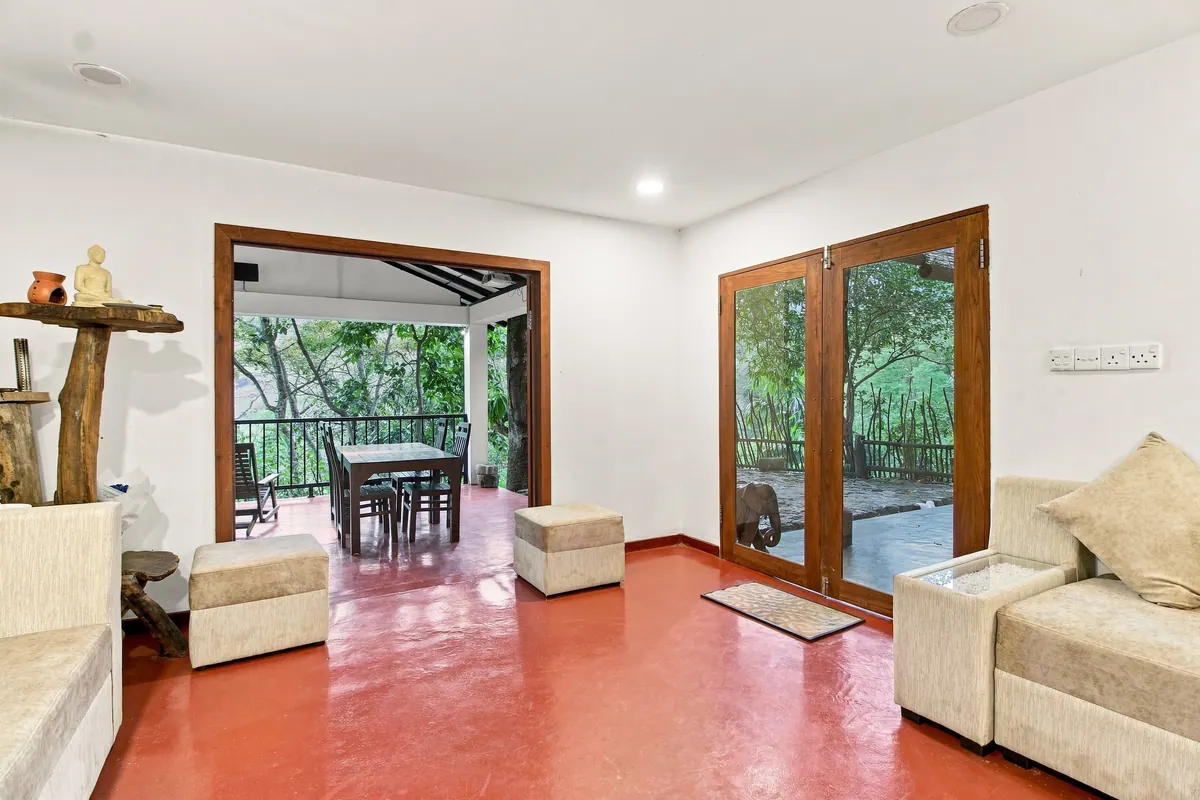 The bungalow lounge, glass doors open onto the veranda and a dining table outside
