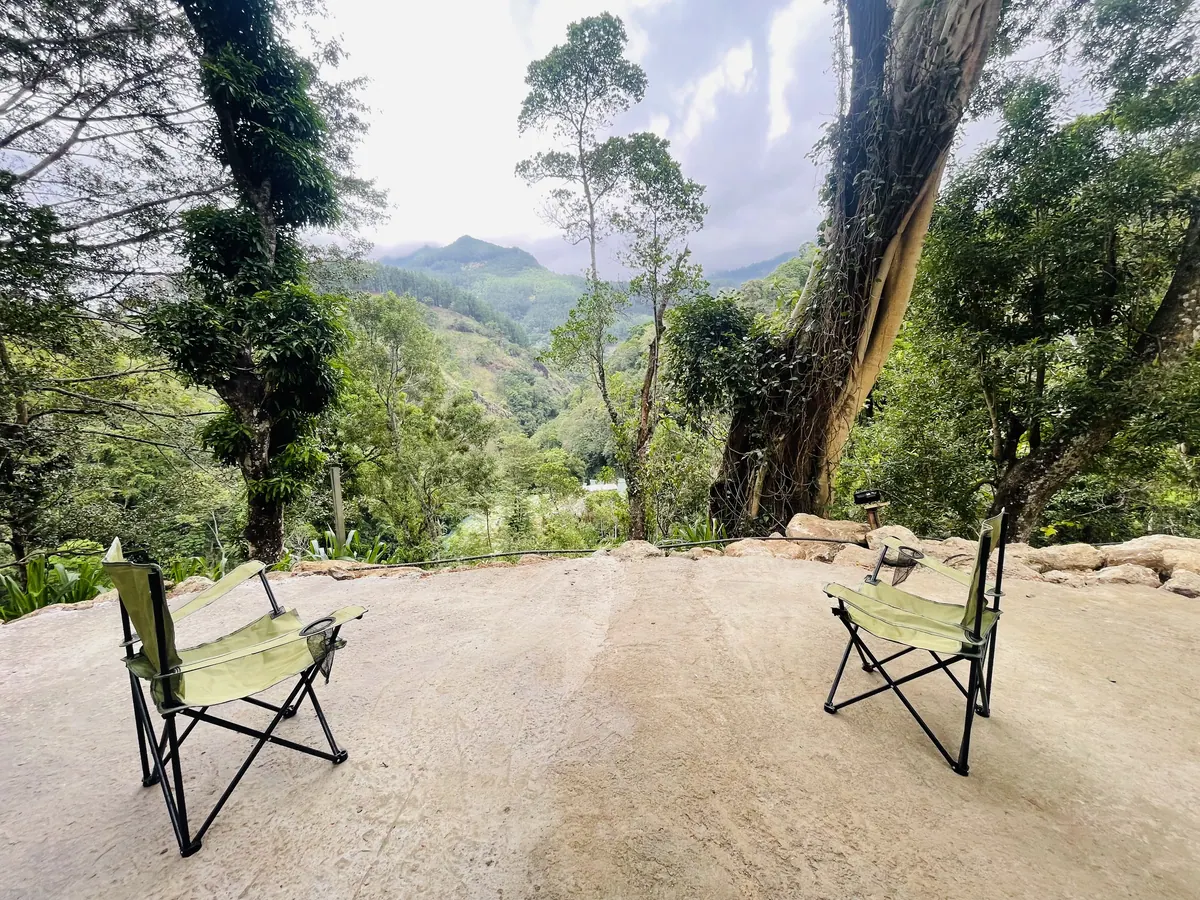 Two camp chairs on the clearing, facing the valley between the trees