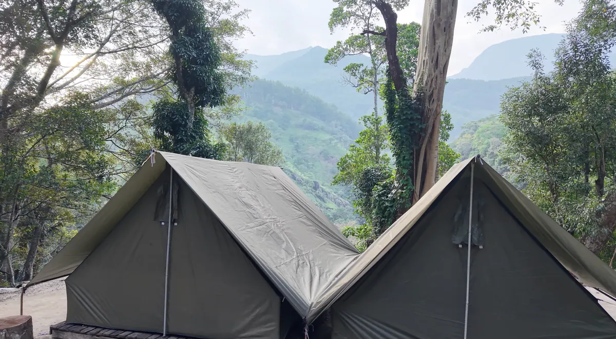 Two canvas ridge tents at the edge of the campsite, the valley falling away behind