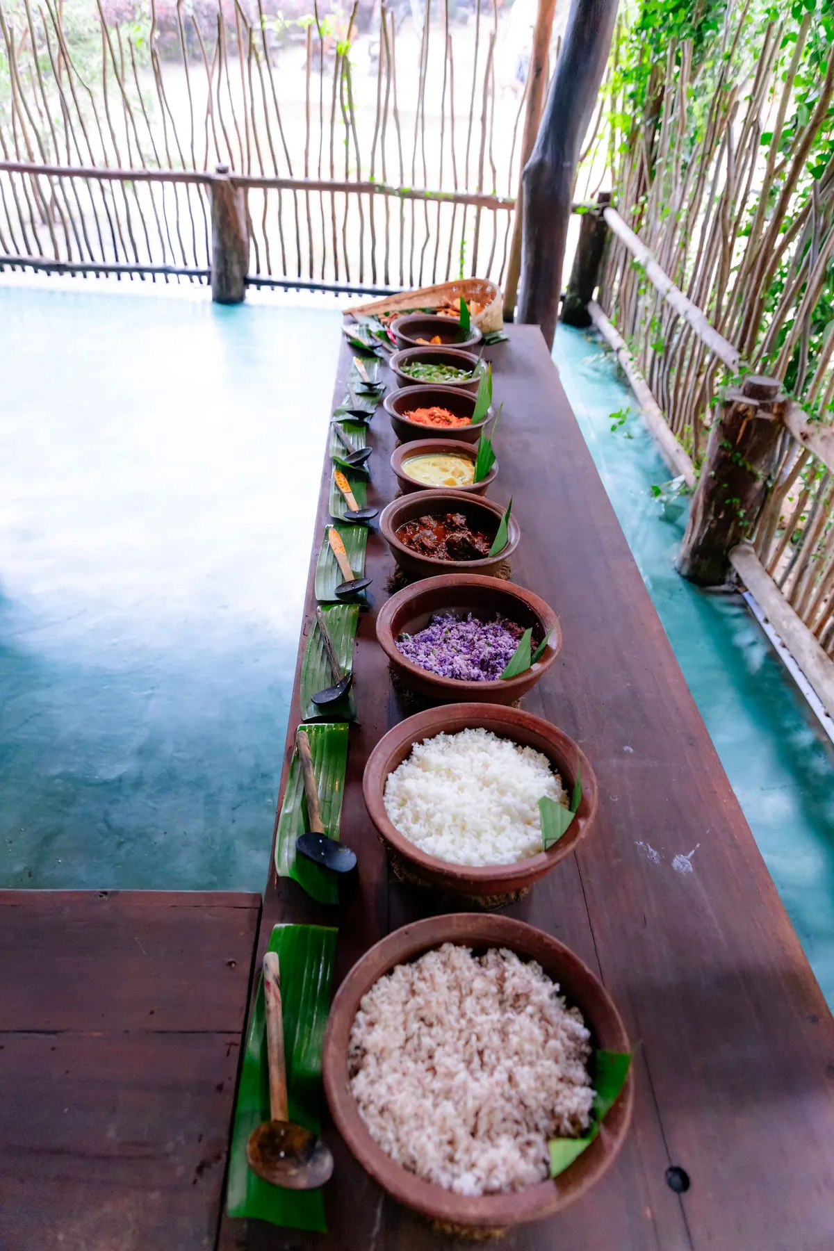 Clay pots of curry and rice running down a long table from above